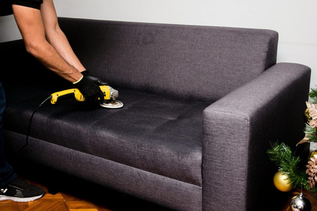 A professional performs sofa cleaning with a grinder in an indoor setting, showcasing efficient service.